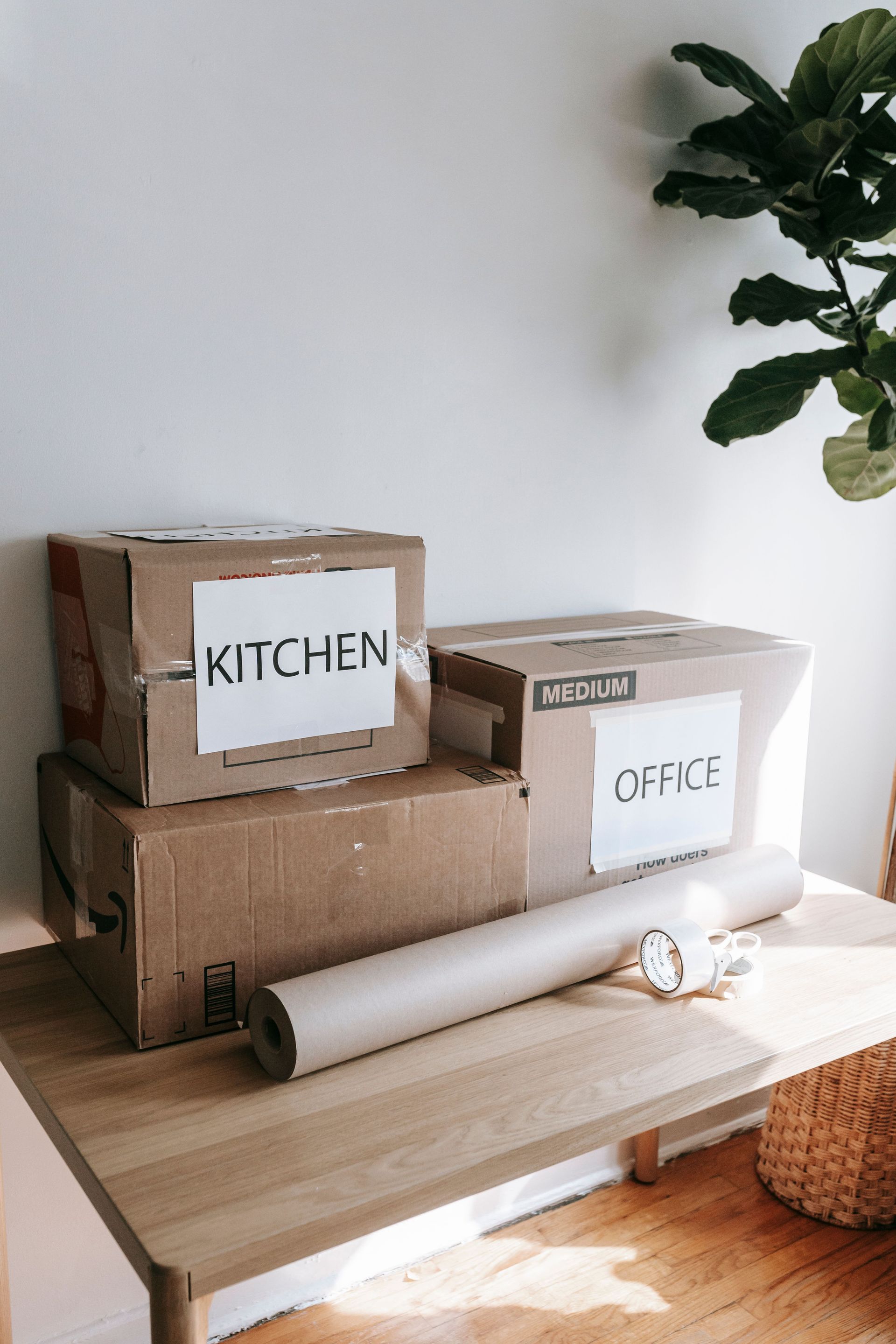 Cardboard boxes labeled for kitchen and office on a wooden table indicating moving day.